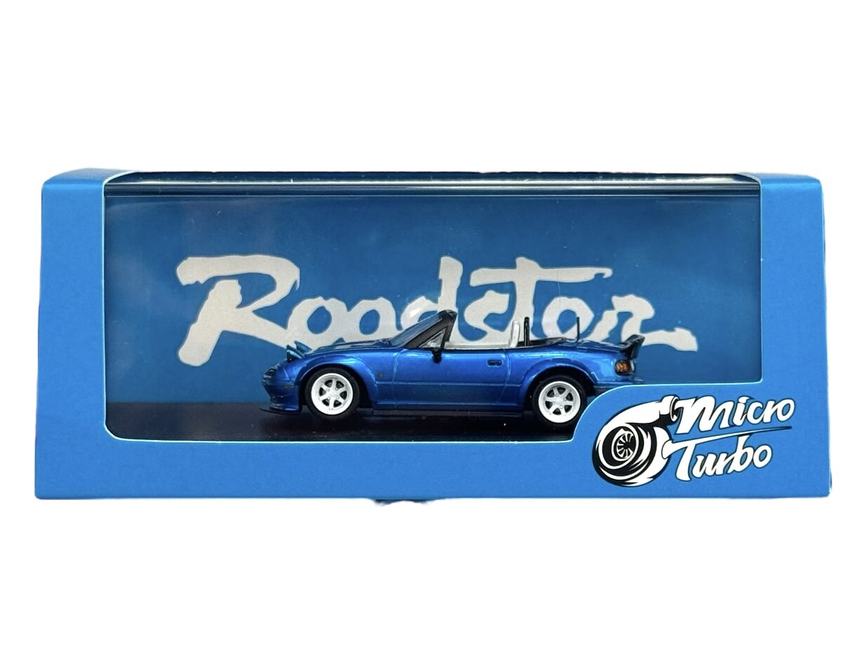 Model samochodu w skali 1:64 w kolorze niebieskim, umieszczony w niebieskim opakowaniu z przezroczystym frontem. Na opakowaniu widoczne są napisy \'Roadster\' i \'Micro Turbo\'.