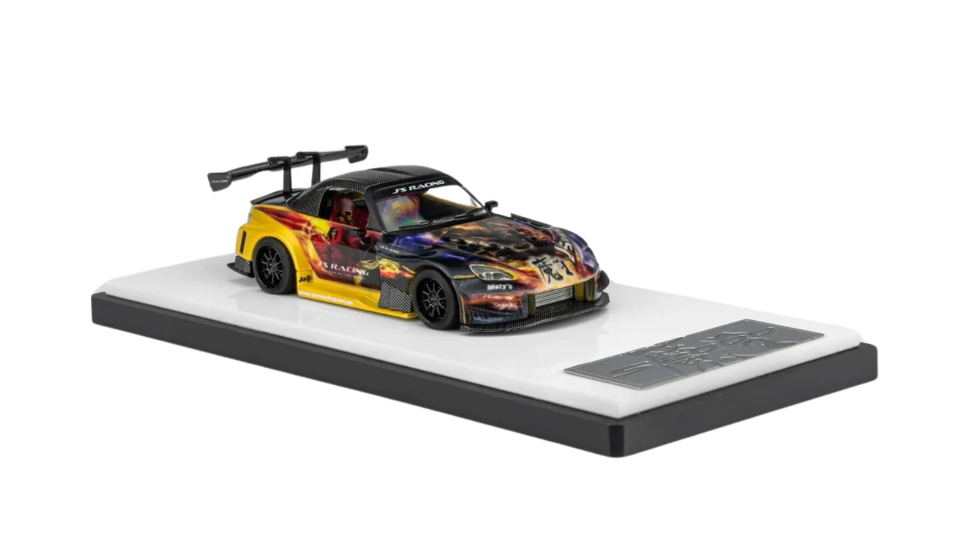 Model samochodu wyścigowego w skali 1:64 z kolorowym, dynamicznym wzorem na karoserii, umieszczony na białej podstawce. Na masce widoczny jest napis \'J\'s Racing\'.