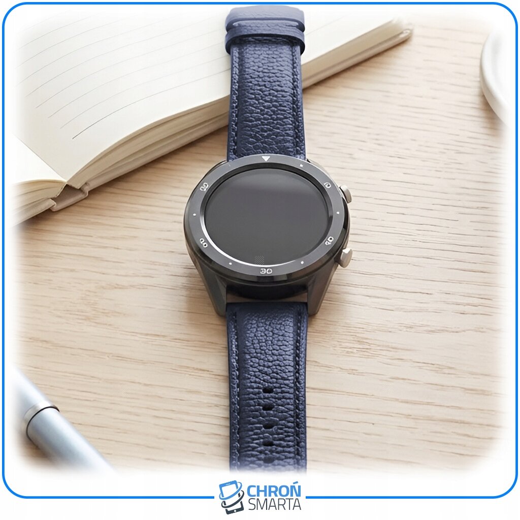 Na drewnianym blacie leży smartwatch z ciemnym, skórzanym paskiem. W tle znajduje się otwarty notes i długopis, a na dole widoczne jest logo \'CHROŃ SMARTA\'.