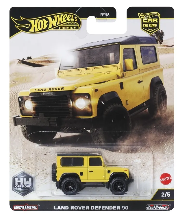 Opakowanie z modelem samochodu Hot Wheels Premium, przedstawiające żółty Land Rover Defender 90. Na opakowaniu widoczne są napisy: \'Hot Wheels Premium\', \'Land Rover Defender 90\', \'HW Off Road\', \'Metal/Metal\', \'Real Riders\', \'FPY86\', \'2/5\' oraz logo Mattel.