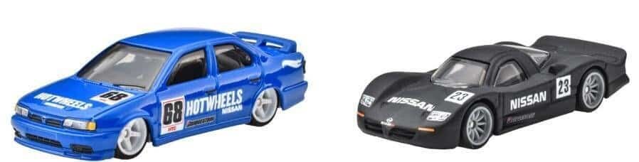 Na obrazie znajdują się dwa metalowe modele samochodów Hot Wheels. Jeden jest niebieski z napisem \'HOT WHEELS\' i numerem \'68\', a drugi czarny z napisem \'NISSAN\' i numerem \'23\'.