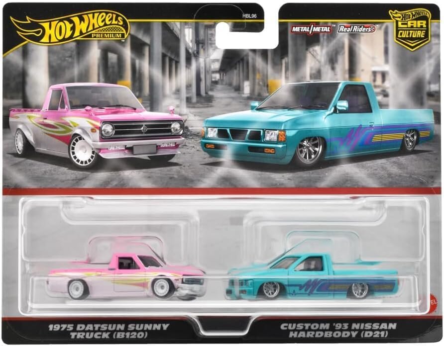 Opakowanie z dwoma modelami samochodów Hot Wheels Premium, przedstawiające różowy 1975 Datsun Sunny Truck (B120) i niebieski Custom \'93 Nissan Hardbody (D21). Na górze widoczne jest logo \'Hot Wheels Premium\' oraz napisy \'Metal/Metal\' i \'Real Riders\'.