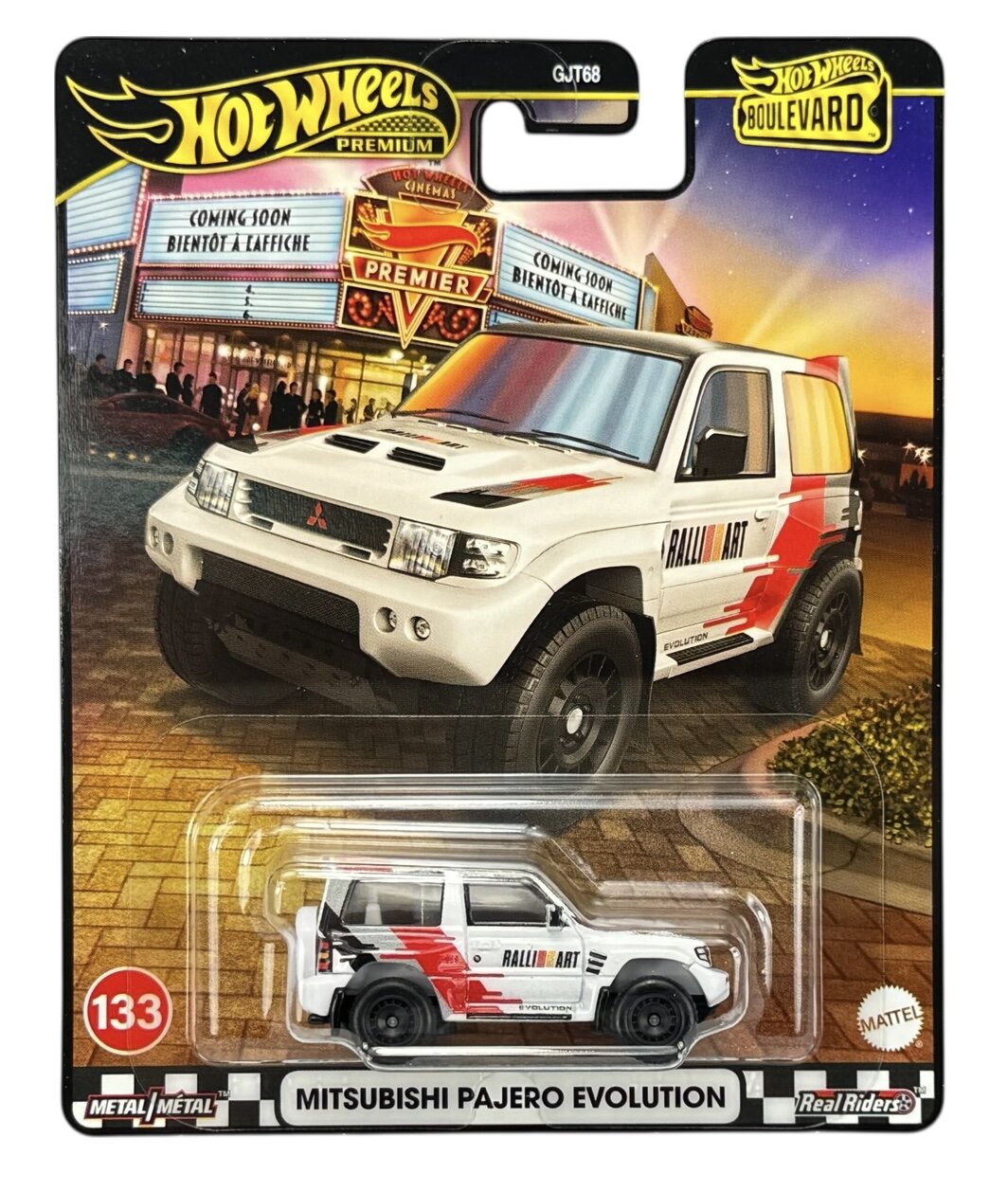 Opakowanie z modelem samochodu Hot Wheels Premium przedstawia białe Mitsubishi Pajero Evolution z czerwonymi i czarnymi detalami. Na opakowaniu widnieje napis \'MITSUBISHI PAJERO EVOLUTION\' oraz logo Hot Wheels Boulevard i Real Riders.