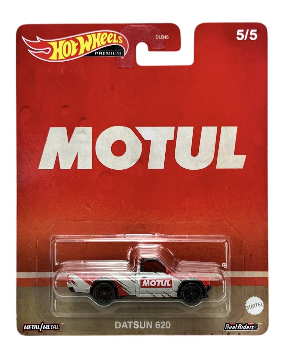 Opakowanie z modelem samochodu Hot Wheels Premium, przedstawiające Datsun 620 z logo \'MOTUL\' na czerwonym tle. Na opakowaniu widnieje napis \'DATSUN 620\' oraz logo \'Mattel\'.