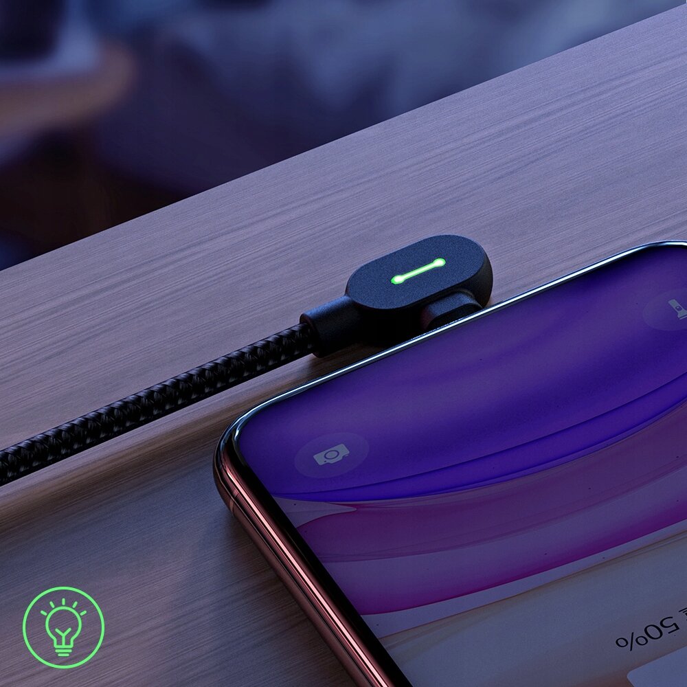 Na drewnianej powierzchni leży smartfon z podłączonym kablem USB-C o kątowym złączu, które ma podświetlenie LED. W rogu obrazu widoczne jest zielone logo w kształcie żarówki.