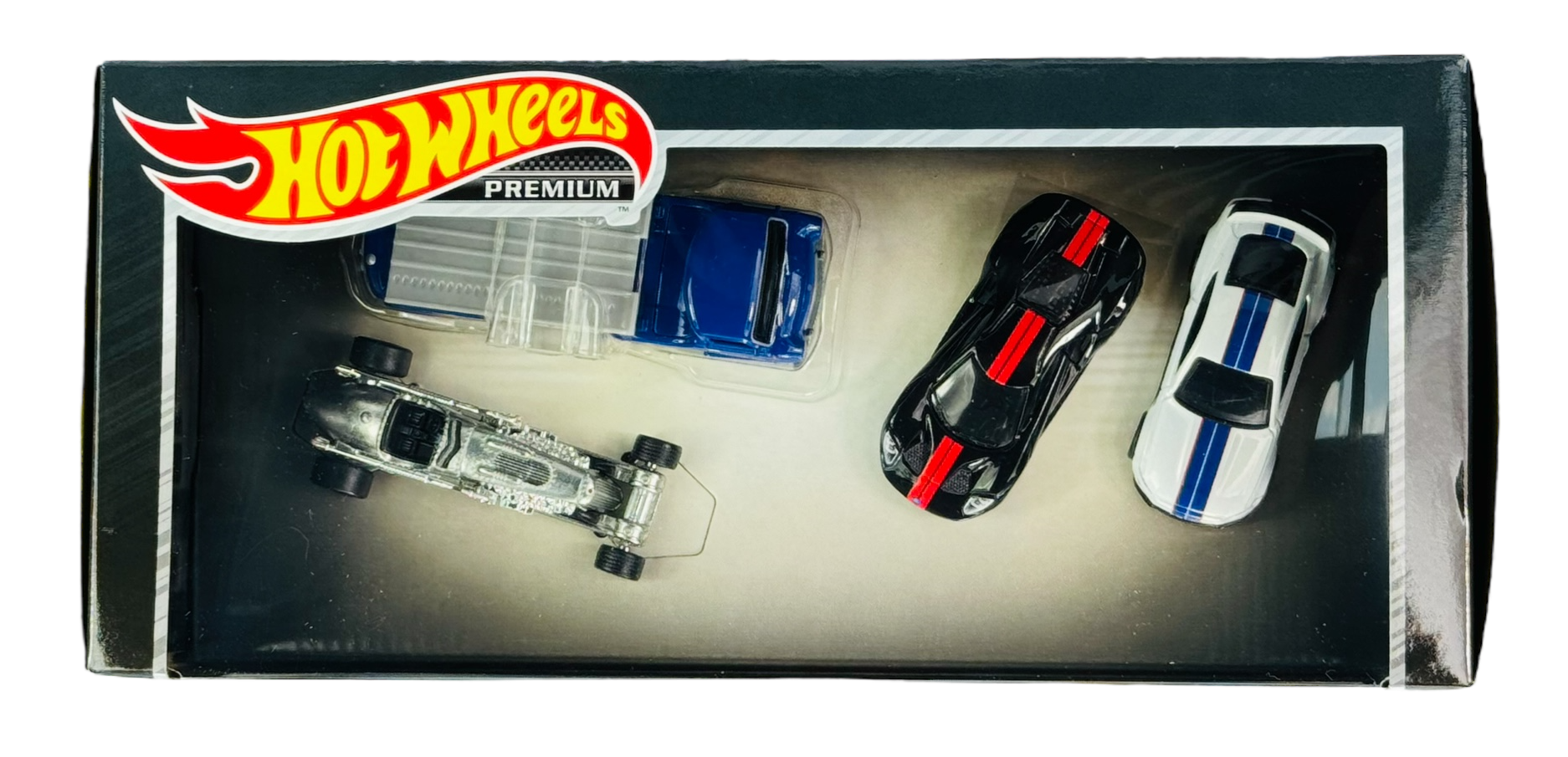 Opakowanie z czterema metalowymi modelami samochodów Hot Wheels Premium, w tym niebieskim, czarnym z czerwonymi paskami, białym z niebieskimi paskami i srebrnym. Logo Hot Wheels Premium znajduje się w lewym górnym rogu opakowania.