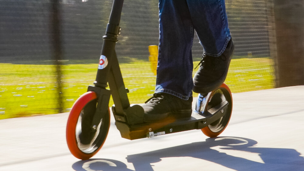 Hulajnoga RAZOR Carbon Lux 13073003 Czarny osoba hamuje zbliżenie na hamulc bezpieczeństwo stabilna jazda tylny błotnik rola hamulca nożnego bezpieczeństwo na drodze łatwa kontrola pojazdu dostosowanie prędkości