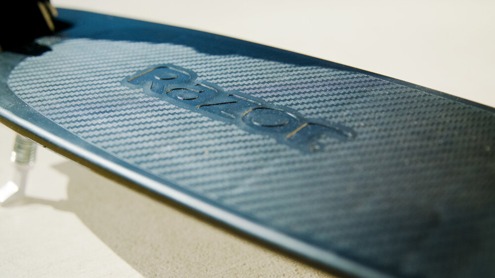 Hulajnoga RAZOR Carbon Lux 13073003 Czarny zbliżenie na platformę lekka platforma z wysokiej jakości aluminium antypoślizgowa powierzchnia szeroki podest o wymiarach 54,8 x 14 cm bezpieczne użytkowanie makymalna waga użytkowanika do 100 kg solidność komfort