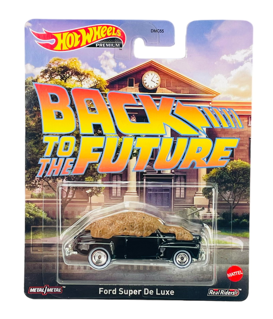 Opakowanie z modelem samochodu Hot Wheels, przedstawiające czarny Ford Super De Luxe. Na tle budynku z zegarem widnieje napis \'BACK TO THE FUTURE\'.