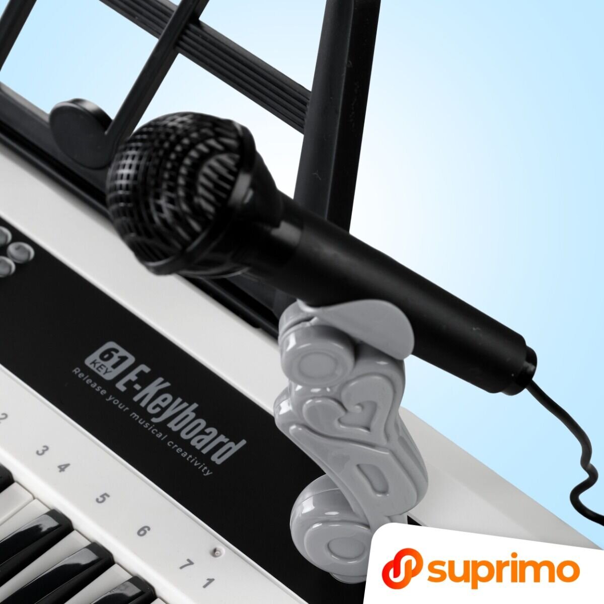 Na obrazie widoczny jest fragment klawiatury z 61 klawiszami oraz mikrofon. Na klawiaturze znajduje się napis \'E-Keyboard Release your musical creativity\', a w rogu widoczne jest logo \'suprimo\'.