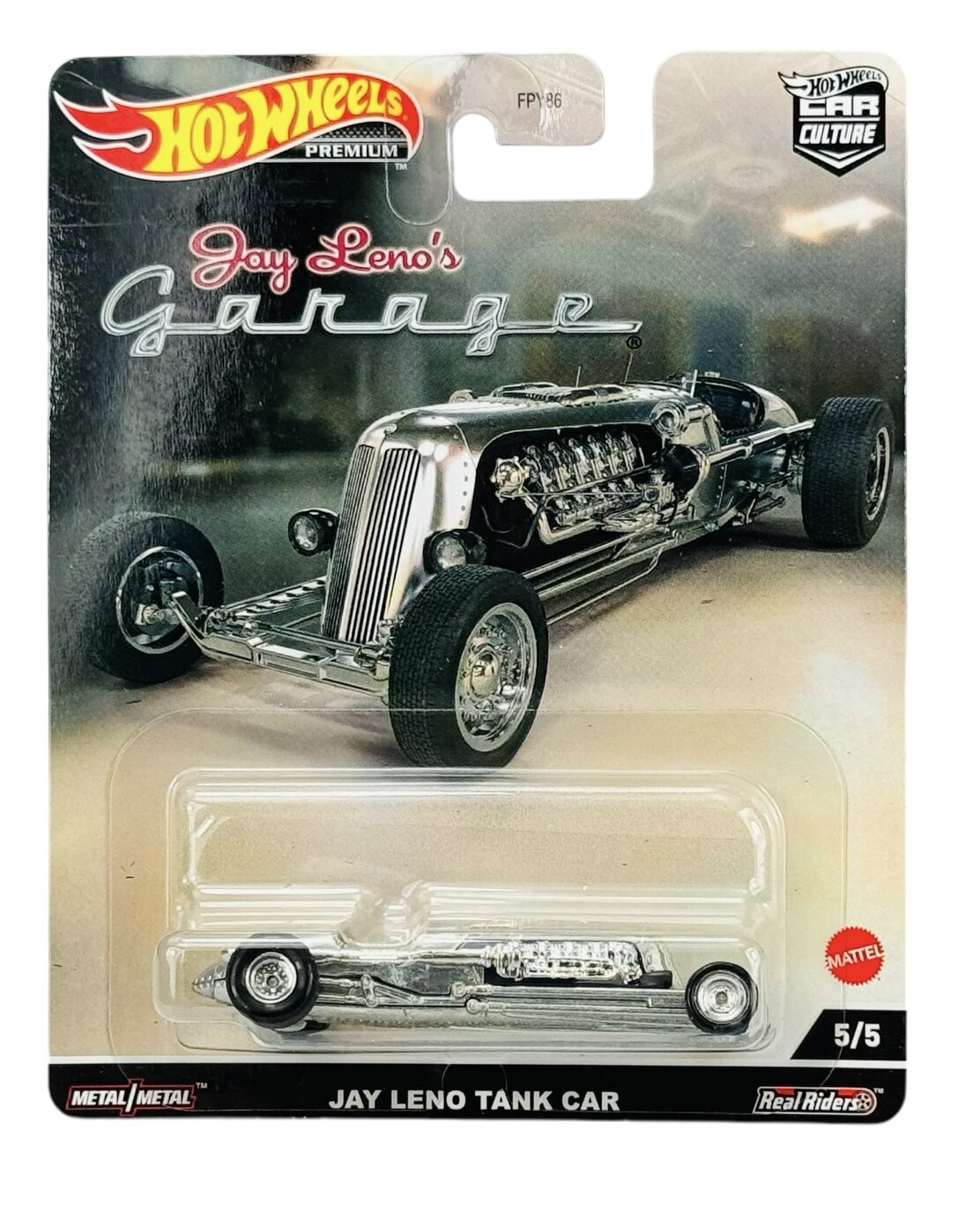 Opakowanie modelu samochodu Hot Wheels z serii Jay Leno\'s Garage, przedstawiające metalowy model Jay Leno Tank Car. Na opakowaniu widoczne są napisy: \'Hot Wheels Premium\', \'Jay Leno\'s Garage\', \'Metal/Metal\', \'Jay Leno Tank Car\', \'5/5\', oraz logo Mattel.