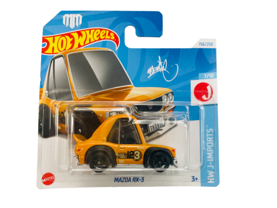 Opakowanie z modelem samochodu Hot Wheels Mazda RX-3 w kolorze pomarańczowym z numerem 23 na boku. Na opakowaniu widoczne są napisy: \'Hot Wheels\', \'156/250\', \'7/10\', \'HW J-IMPORTS\', \'MAZDA RX-3\'.