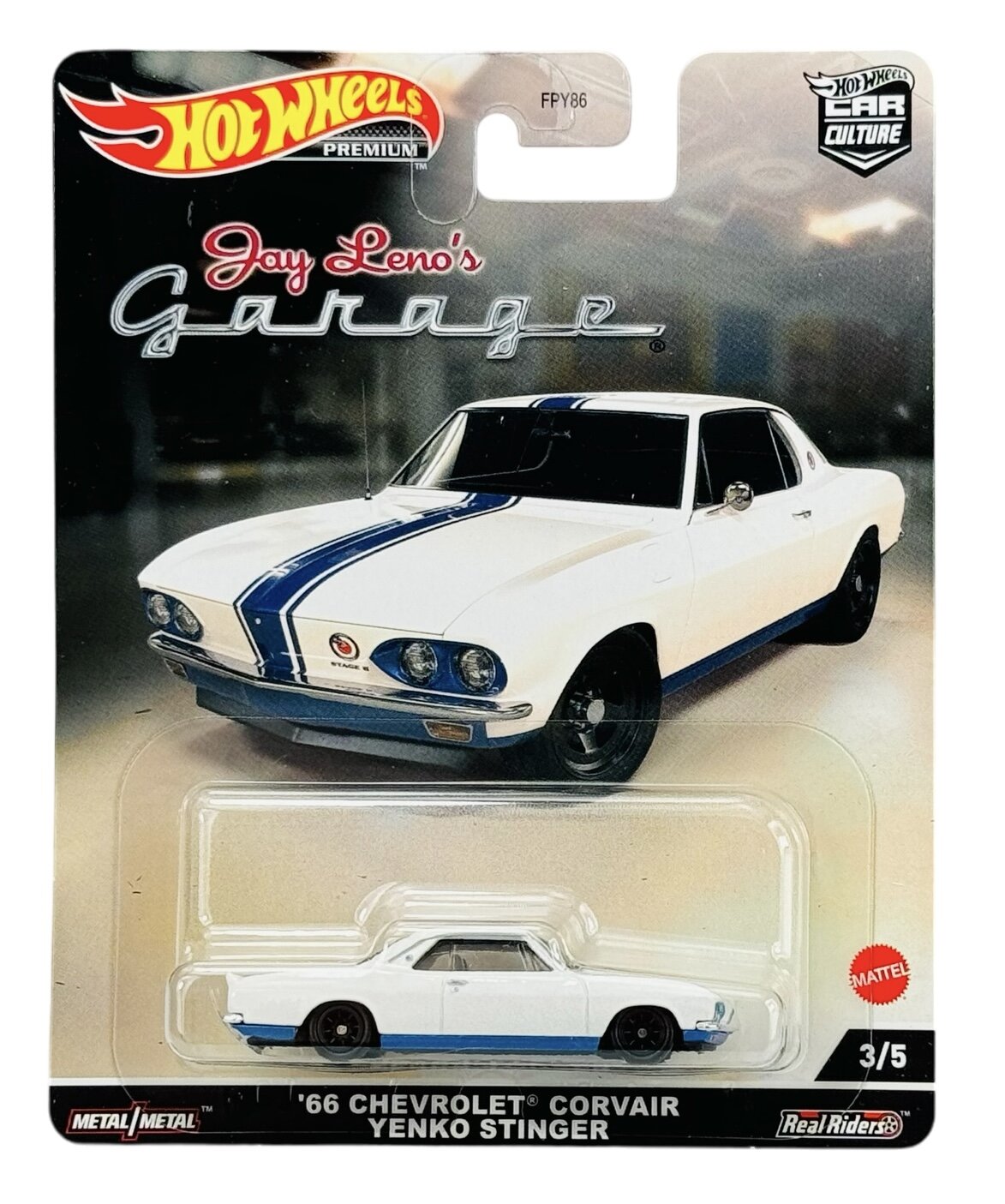 Opakowanie modelu samochodu Hot Wheels z serii Jay Leno\'s Garage, przedstawiające biały samochód z niebieskim pasem. Na dole opakowania widnieje napis: \'66 Chevrolet Corvair Yenko Stinger\'.