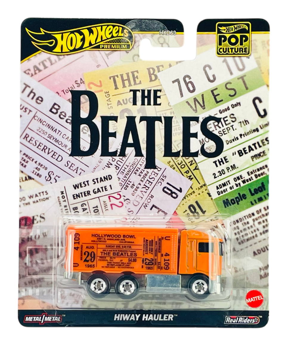 Opakowanie Hot Wheels Premium Pop Culture z modelem ciężarówki Hiway Hauler, ozdobione grafiką związaną z The Beatles. Widoczne są różnokolorowe bilety koncertowe oraz logo Hot Wheels i Mattel.