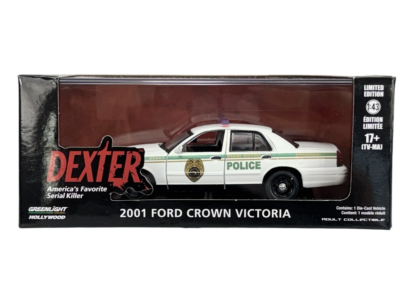 Model samochodu policyjnego 2001 Ford Crown Victoria w skali 1:43 w opakowaniu z napisem \'DEXTER America\'s Favorite Serial Killer\'. Widoczne są również napisy \'POLICE\', \'LIMITED EDITION\', \'17+\' oraz logo \'Greenlight Hollywood\'.