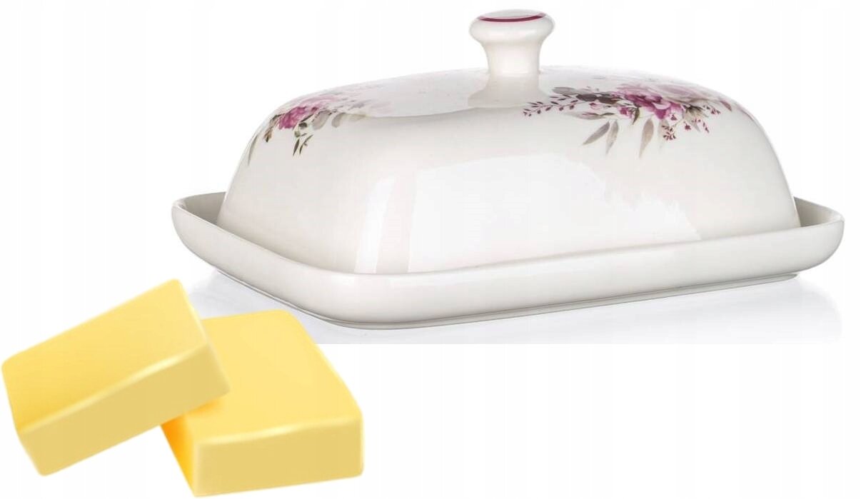 Ceramiczna maselniczka z pokrywką ozdobioną różowymi kwiatami, obok której leżą dwa kawałki masła.