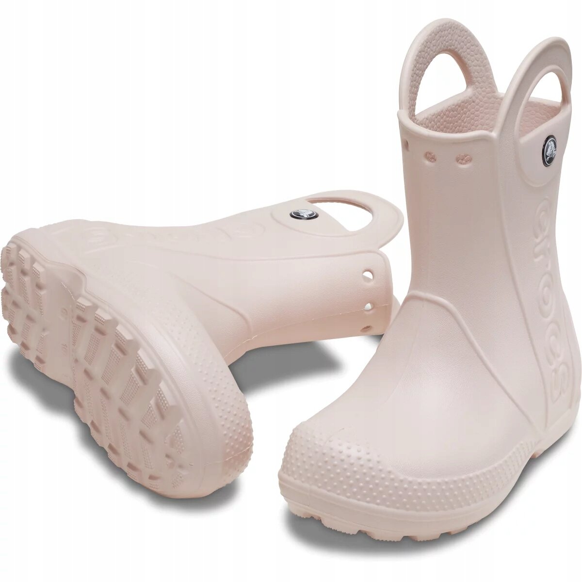 Na obrazie widoczne są jasnoróżowe dziecięce kalosze z uchwytami na górze. Na boku jednego z butów znajduje się napis \'crocs\'.