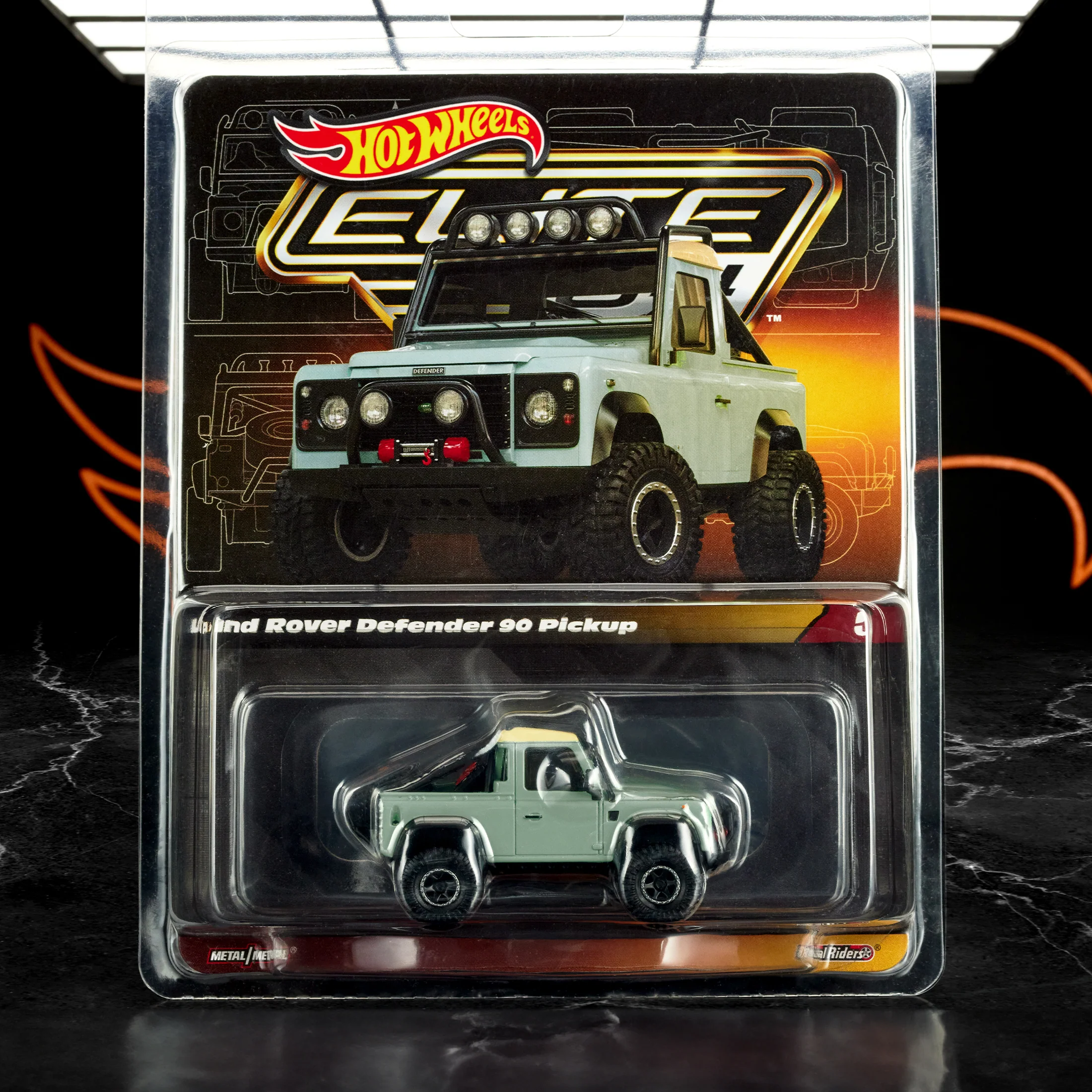 Opakowanie z modelem samochodu Hot Wheels Elite 64, przedstawiające Land Rover Defender 90 Pickup. Widoczny jest tekst: \'Land Rover Defender 90 Pickup\' oraz logo Hot Wheels.