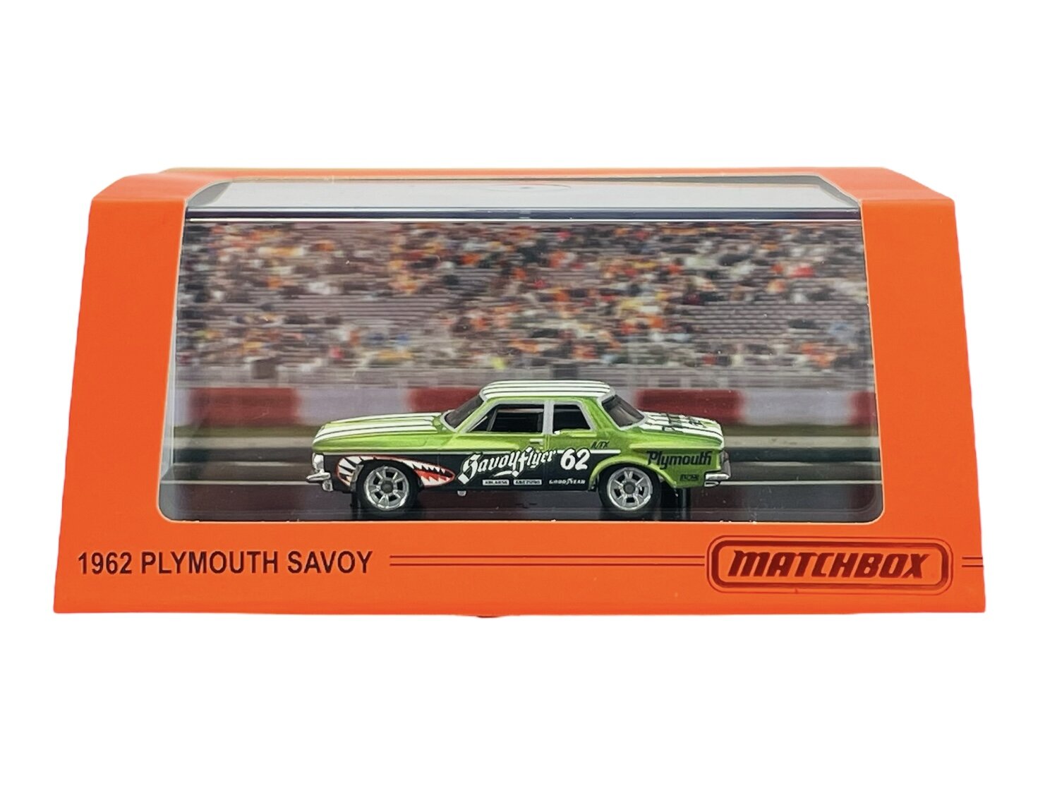 Model samochodu 1962 Plymouth Savoy w zielonym kolorze, umieszczony w przezroczystym pudełku z pomarańczową ramką. Na pudełku widnieje napis \'1962 PLYMOUTH SAVOY\' oraz logo \'MATCHBOX\'.