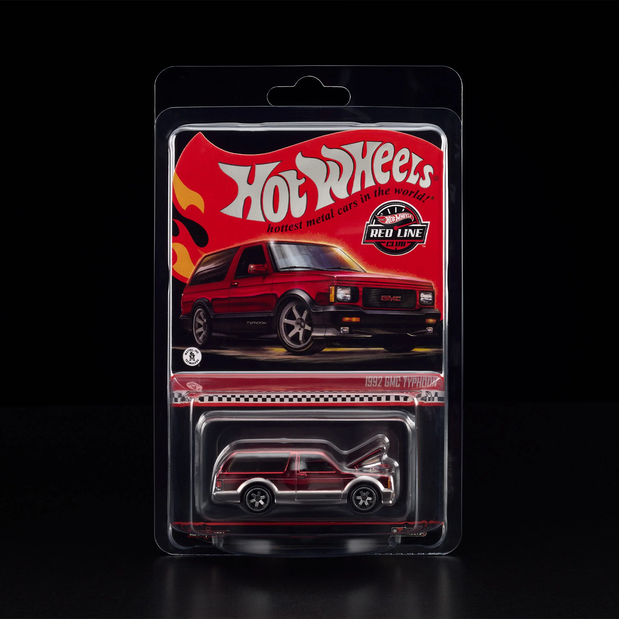 Opakowanie z modelem samochodu Hot Wheels, przedstawiające czerwony pojazd z napisem \'1992 GMC Typhoon\'. Widoczne logo \'Red Line Club\' oraz tekst \'hottest metal cars in the world\'.