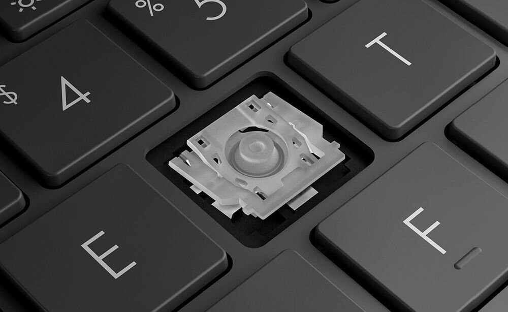 Zbliżenie na klawiaturę laptopa z usuniętym klawiszem, ukazującym mechanizm pod klawiszem. Widoczne są klawisze z literami E, T, F oraz cyfrą 4.