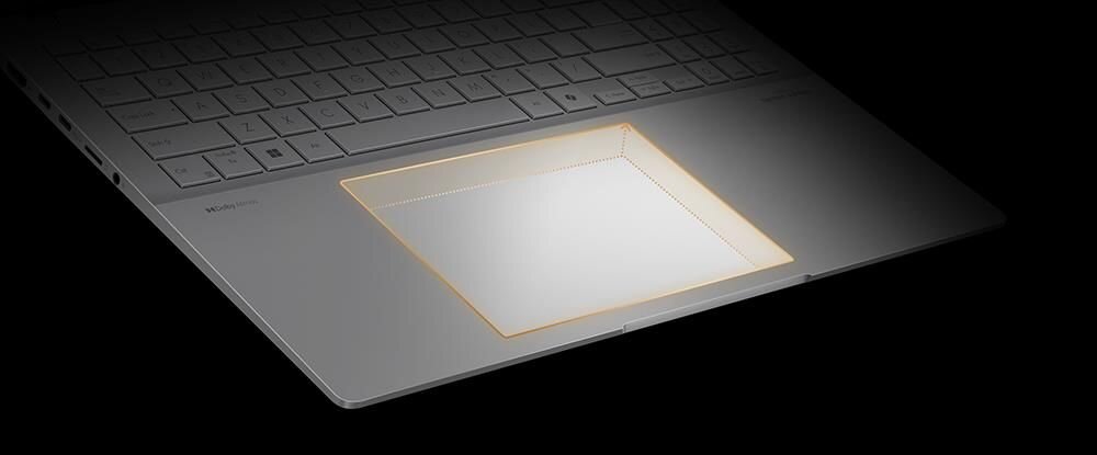 Obraz przedstawia klawiaturę laptopa z podświetlonym touchpadem. Klawisze są w jasnym kolorze, a touchpad jest otoczony delikatnym, pomarańczowym światłem.