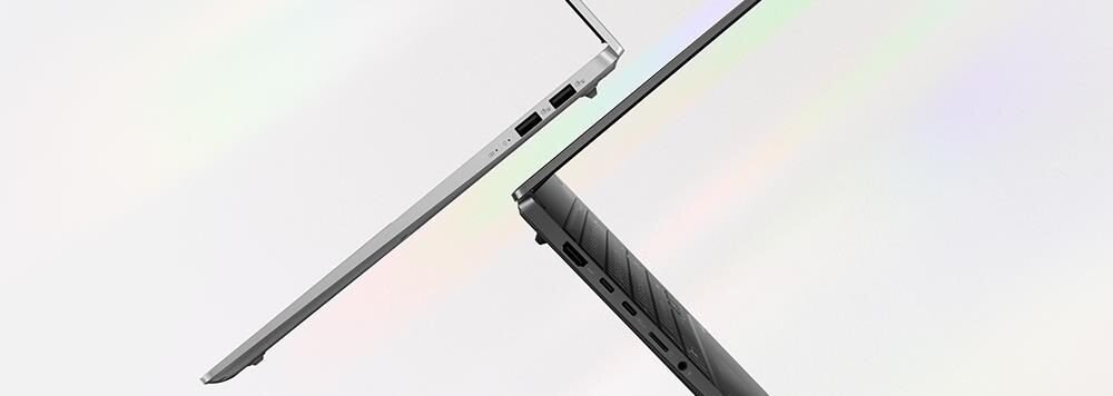 Dwa laptopy w różnych kolorach są otwarte pod kątem, ukazując boczne porty i smukły profil. Tło jest jasne z delikatnymi, tęczowymi refleksami.