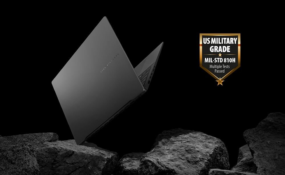 Ciemny laptop unosi się nad kamieniami na czarnym tle. Obok widoczna jest odznaka z napisem \'US MILITARY GRADE MIL-STD 810H Multiple Tests Passed\'.