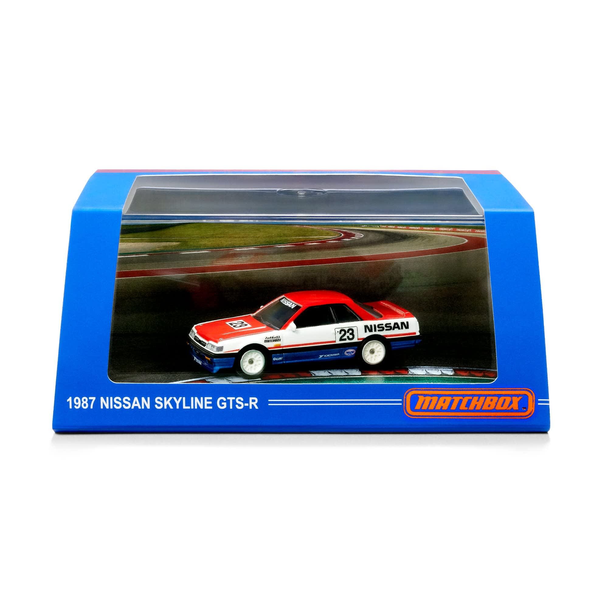 Model samochodu 1987 Nissan Skyline GTS-R w opakowaniu z niebieską ramką i logo \'MATCHBOX\'. Na opakowaniu widnieje napis \'1987 NISSAN SKYLINE GTS-R\'.