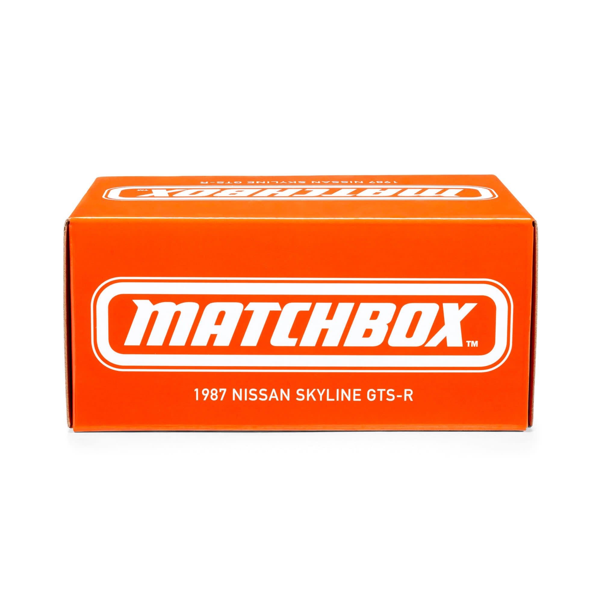 Pomarańczowe pudełko z białym logo \'MATCHBOX\' oraz napisem \'1987 NISSAN SKYLINE GTS-R\'.
