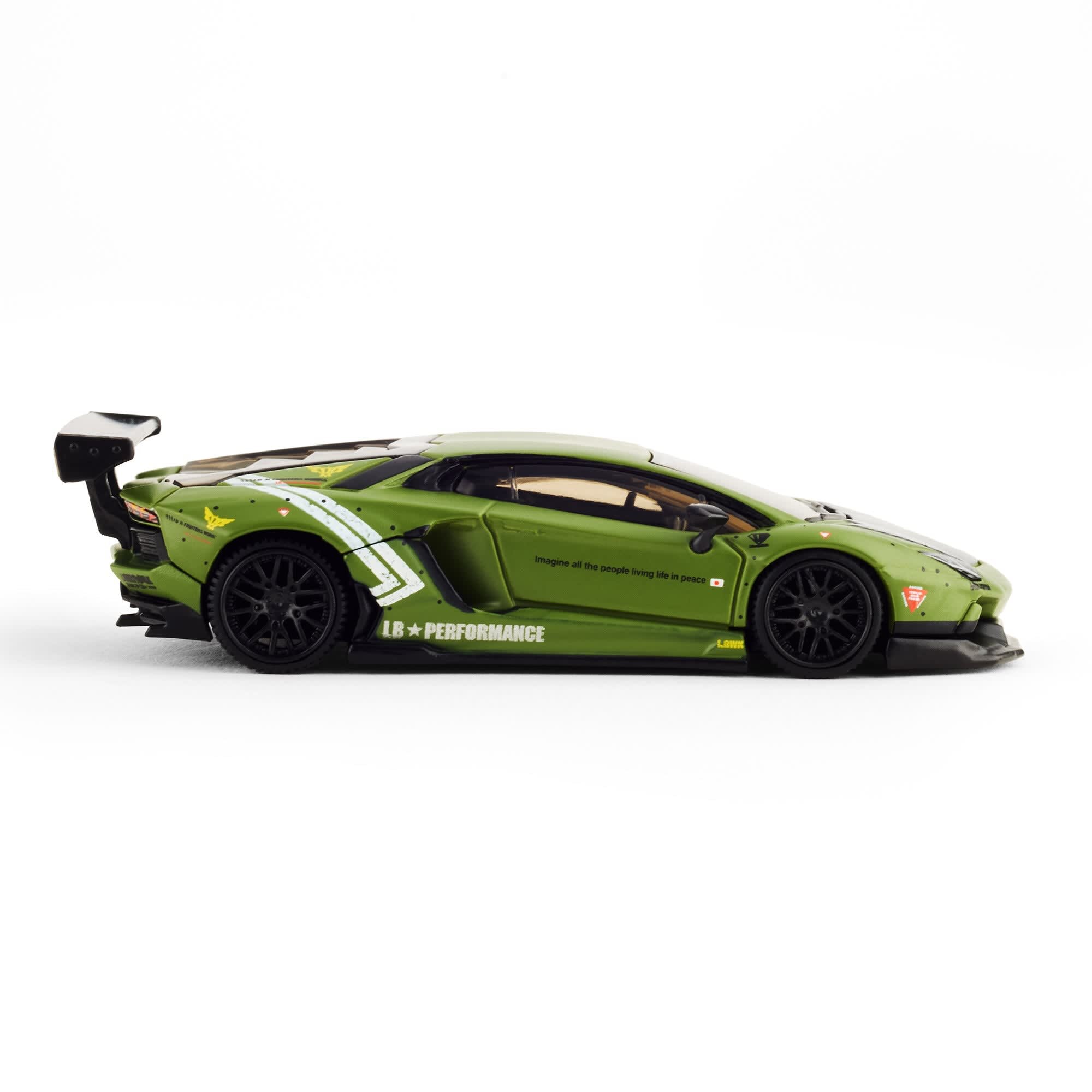 Model samochodu w skali 1:64 przedstawia zielone Lamborghini Aventador z czarnymi felgami i dużym tylnym spojlerem. Na boku widoczne są napisy \'LB PERFORMANCE\' oraz \'Imagine all the people living life in peace\'.