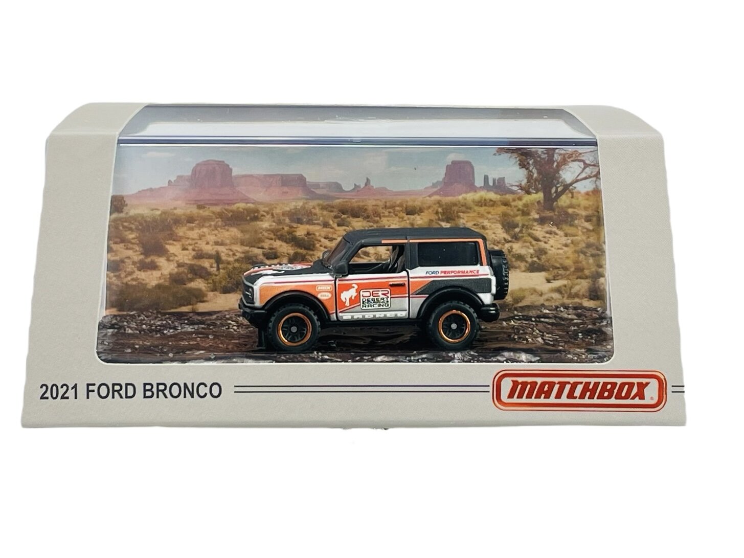 Model samochodu 2021 Ford Bronco w opakowaniu z przezroczystym frontem, na tle pustynnego krajobrazu. Na opakowaniu widnieje napis \'2021 FORD BRONCO\' oraz logo \'Matchbox\'.