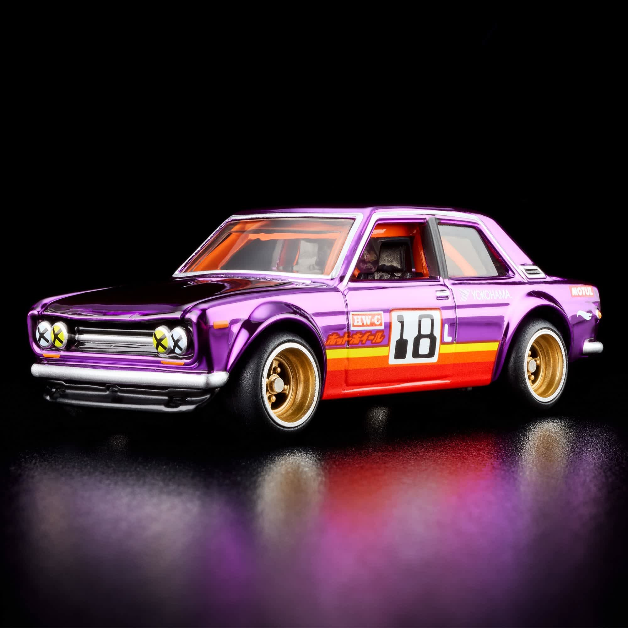 Model samochodu w kolorze fioletowym z numerem 18 na boku, posiada złote felgi i naklejki z napisami \'HW-C\', \'Yokohama\' oraz \'Motul\'. Tło jest czarne, co podkreśla połysk metalowego wykończenia modelu.
