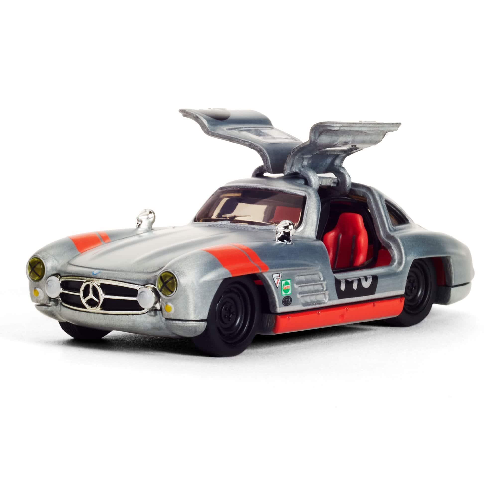 Model samochodu w skali 1:64 przedstawiający srebrny Mercedes-Benz 300 SL z otwartymi drzwiami typu gullwing. Na karoserii widoczne są czerwone pasy i numer 722, a wnętrze jest czerwone.