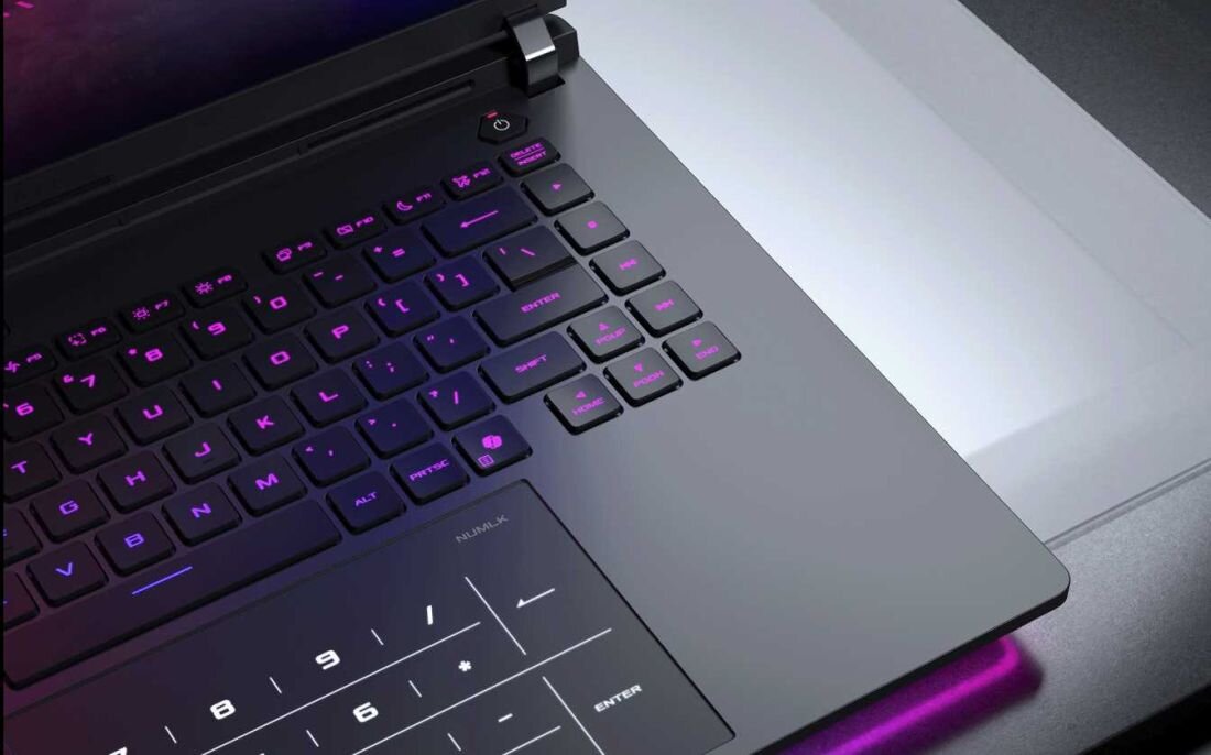 Obraz przedstawia klawiaturę laptopa z podświetleniem RGB, widoczne są klawisze numeryczne oraz touchpad z oznaczeniami numerycznymi. Laptop ma nowoczesny design z metalicznym wykończeniem.