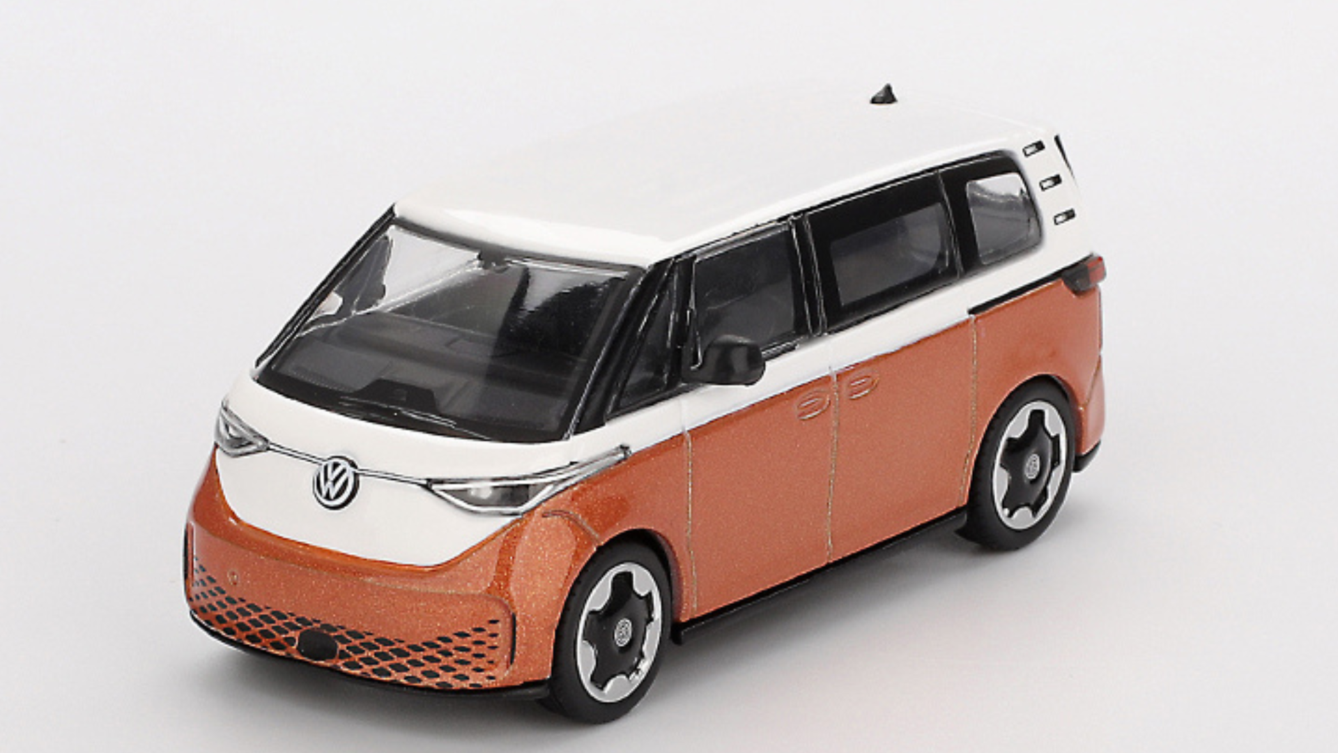 Model samochodu w skali 1:64, przedstawiający pomarańczowo-biały pojazd z logo VW na przodzie. Samochód ma czarne szyby i charakterystyczne felgi.