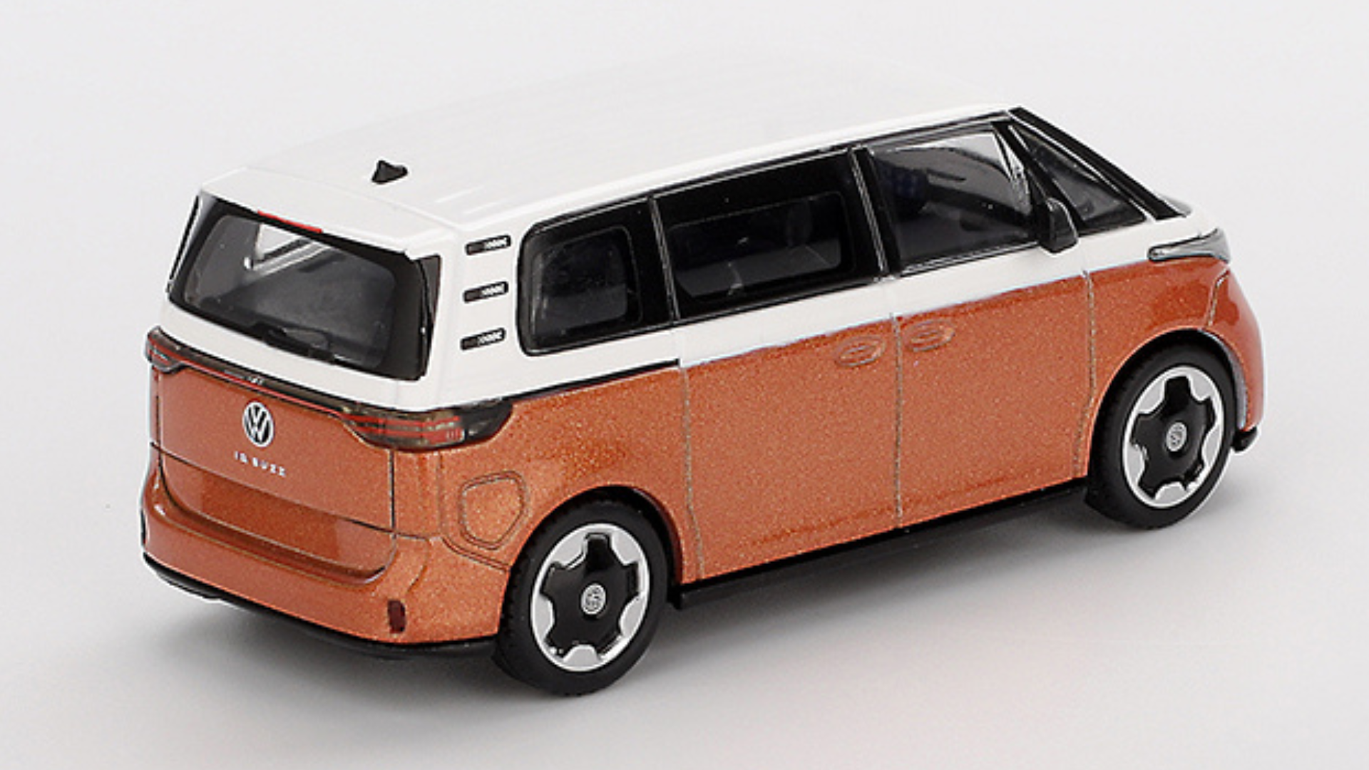 Model samochodu w skali 1:64, przedstawiający pomarańczowo-biały pojazd z logo VW na tylnej klapie. Samochód ma czarne felgi i przeszklone okna.