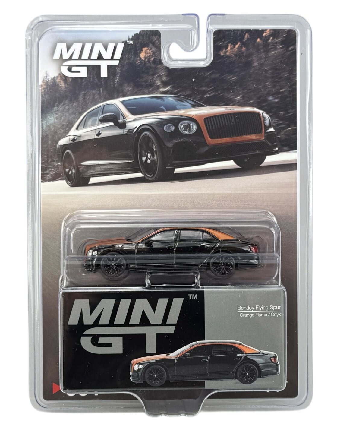 Opakowanie z modelem samochodu w skali 1:64, przedstawiające czarny samochód z pomarańczowymi akcentami. Widoczny tekst: \'MINI GT\' oraz \'Bentley Flying Spur Orange Flame / Onyx\'.
