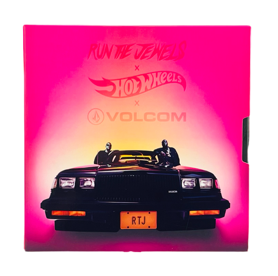 Na obrazie widoczny jest przód czarnego samochodu z tablicą rejestracyjną \'RTJ\', na tle różowego gradientu. Nad samochodem znajdują się logotypy: \'Run The Jewels\', \'Hot Wheels\' i \'Volcom\'.