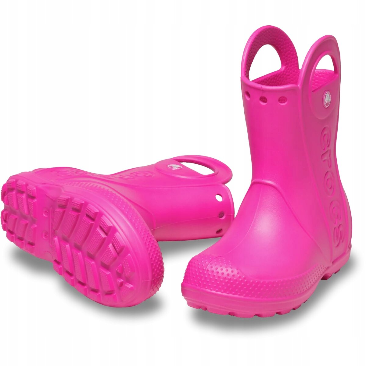 Różowe dziecięce kalosze z uchwytami na górze i wyraźnym bieżnikiem na podeszwie. Na boku widoczny jest napis \'crocs\'.