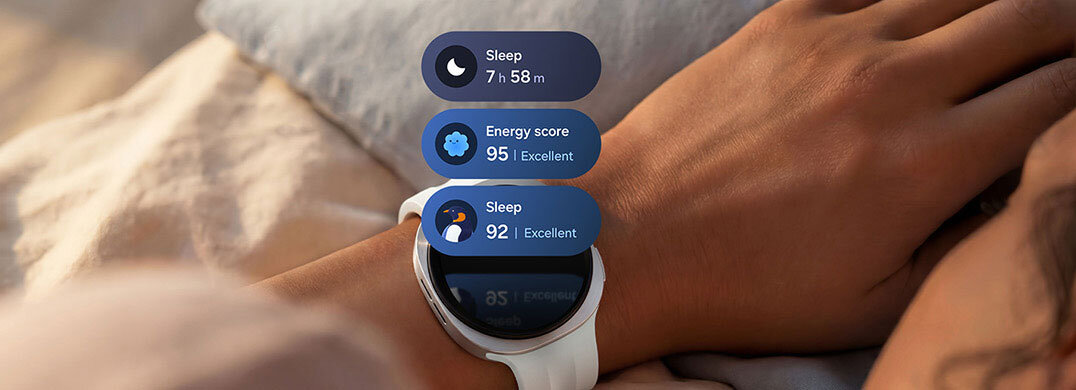 Osoba nosi smartwatch z białym paskiem, na ekranie widoczne są informacje: \'Sleep 7 h 58 m\', \'Energy score 95 | Excellent\', \'Sleep 92 | Excellent\'.