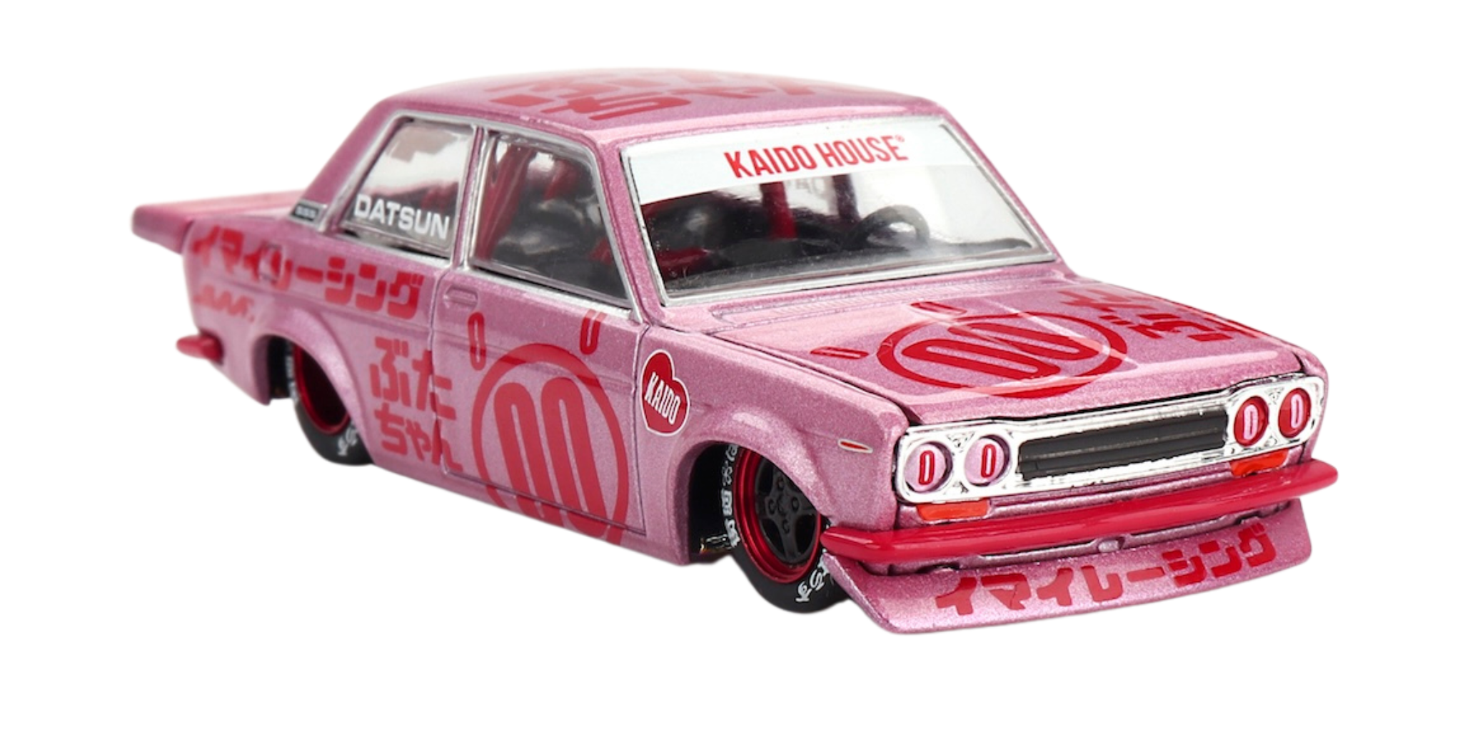 Model samochodu w kolorze różowym z czerwonymi napisami, na masce widoczny napis \'KAIDO HOUSE\'. Na bokach pojazdu znajdują się różne symbole i napisy, w tym \'DATSUN\'.