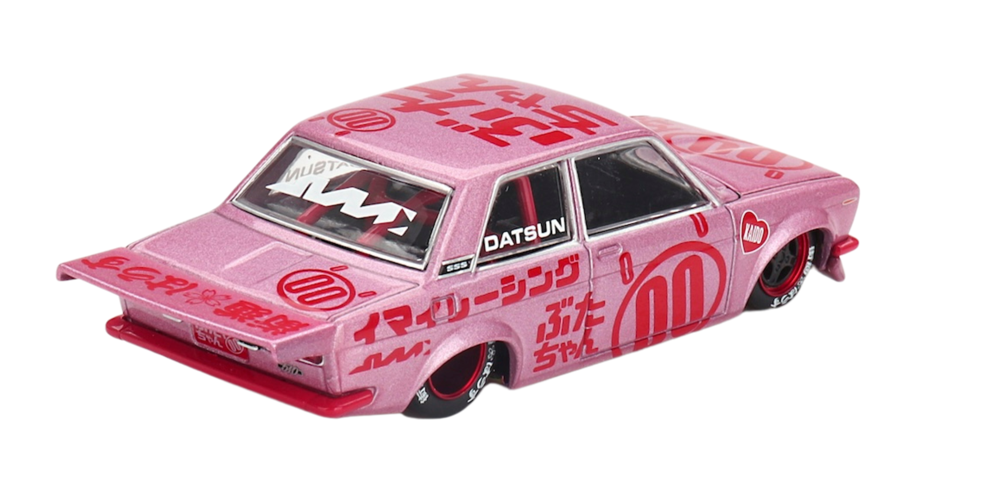 Model samochodu w kolorze różowym z czerwonymi napisami i grafikami, w tym logo \'DATSUN\' na bocznej szybie. Samochód ma sportowy wygląd z dużym tylnym spojlerem i czarnymi felgami z czerwonymi akcentami.