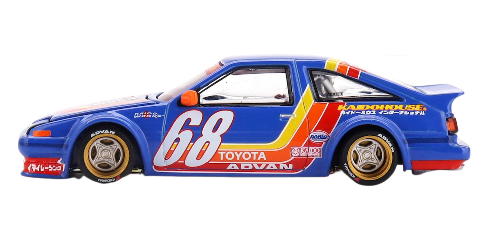 Model samochodu w skali 1:64, przedstawiający niebieski pojazd z numerem 68 i napisami \'TOYOTA\' oraz \'ADVAN\'. Na boku widoczne są kolorowe pasy i logo \'KAIDO HOUSE\'.