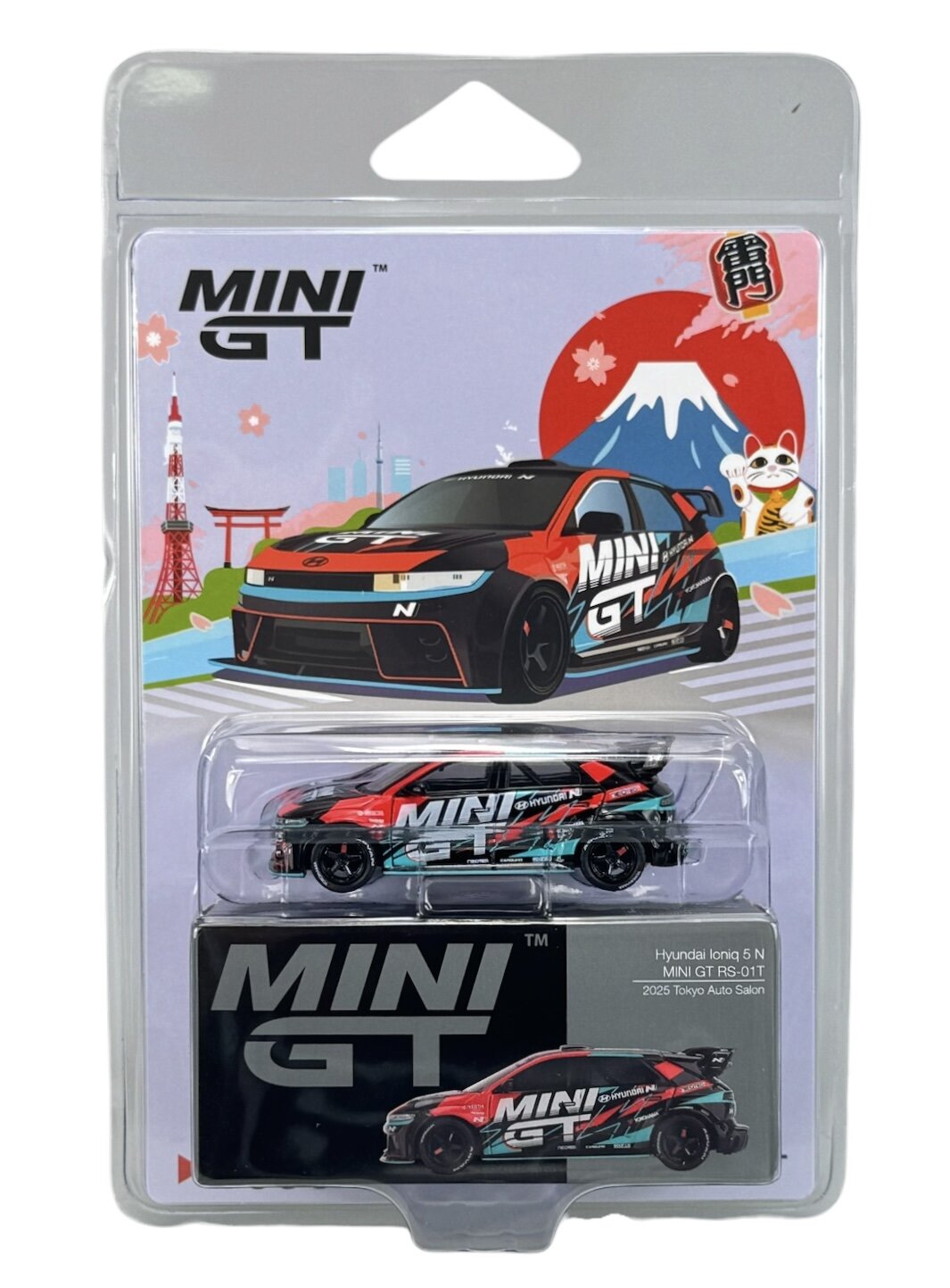 Opakowanie z modelem samochodu Mini GT, przedstawiające czerwono-czarny pojazd z napisem \'MINI GT\'. W tle ilustracja z górą, wieżą i symbolem kota, a na opakowaniu widoczny jest tekst \'Hyundai Ioniq 5 N MINI GT RS-01T 2025 Tokyo Auto Salon\'.