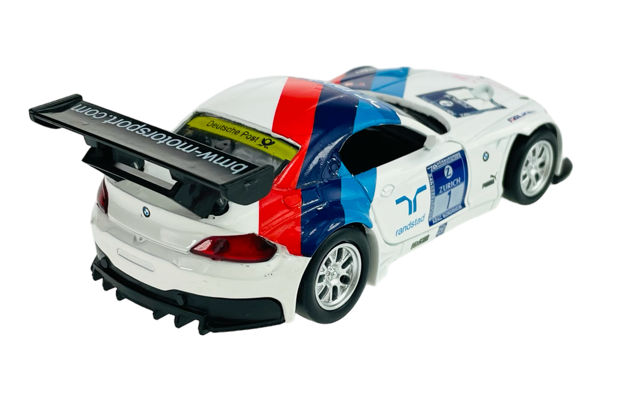 Model samochodu wyścigowego w skali 1:38, w kolorze białym z czerwono-niebieskimi pasami i czarnym tylnym spojlerem. Na samochodzie widoczne są logotypy, w tym \'bmw-motorsport.com\' i \'Deutsche Post\'.
