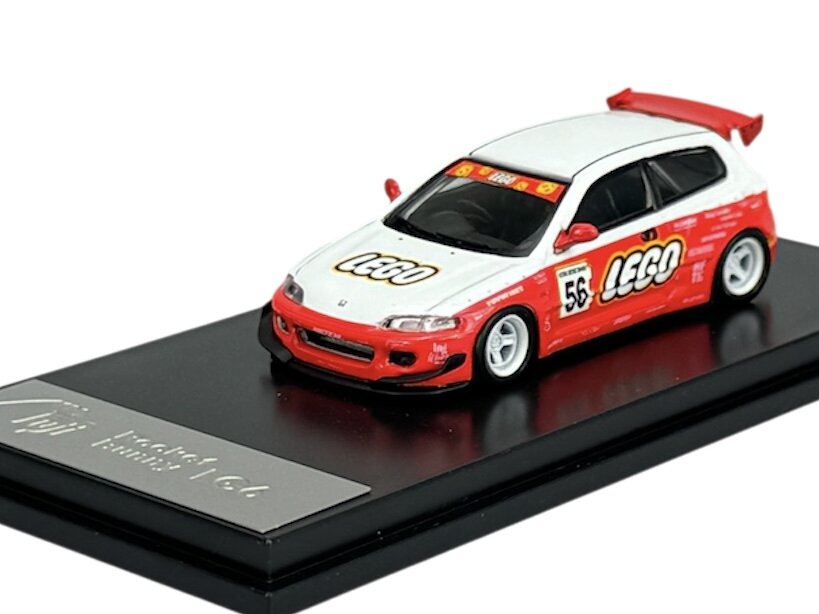 Model samochodu w skali 1:64 z napisem \'LEGO\' na białym tle z czerwonymi akcentami, umieszczony na czarnej podstawce z napisem \'Rocket bunny 1/64\'.