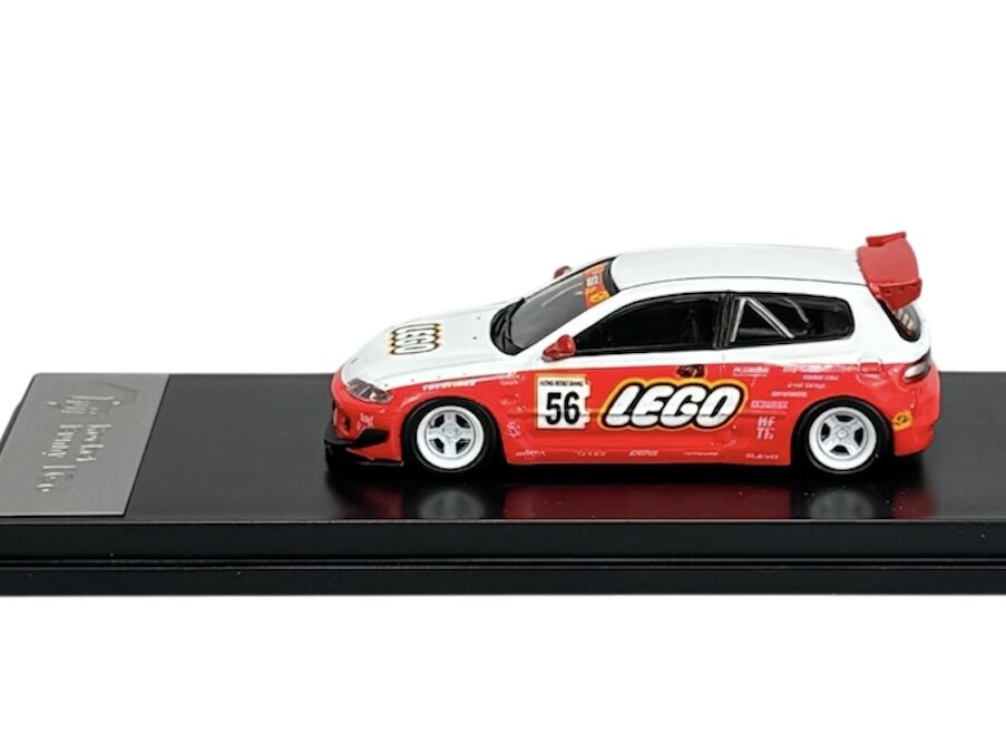 Model samochodu w skali 1:64 z napisem \'LEGO\' na boku, umieszczony na czarnej podstawce. Samochód ma biało-czerwone malowanie z numerem 56 i czerwonym spojlerem.