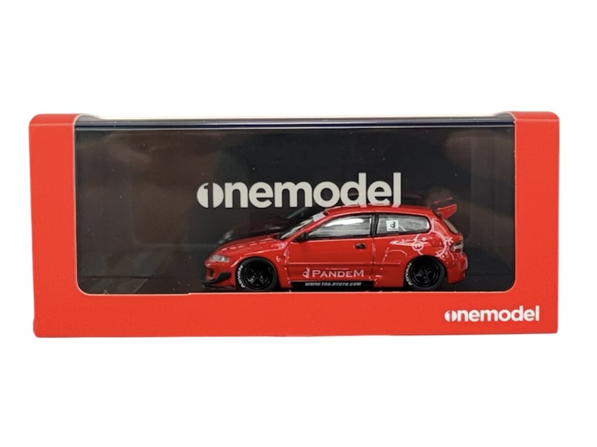 Model samochodu w czerwonym kolorze znajduje się w przezroczystym opakowaniu z napisem \'onemodel\'. Na boku samochodu widoczny jest napis \'Pandem\'.