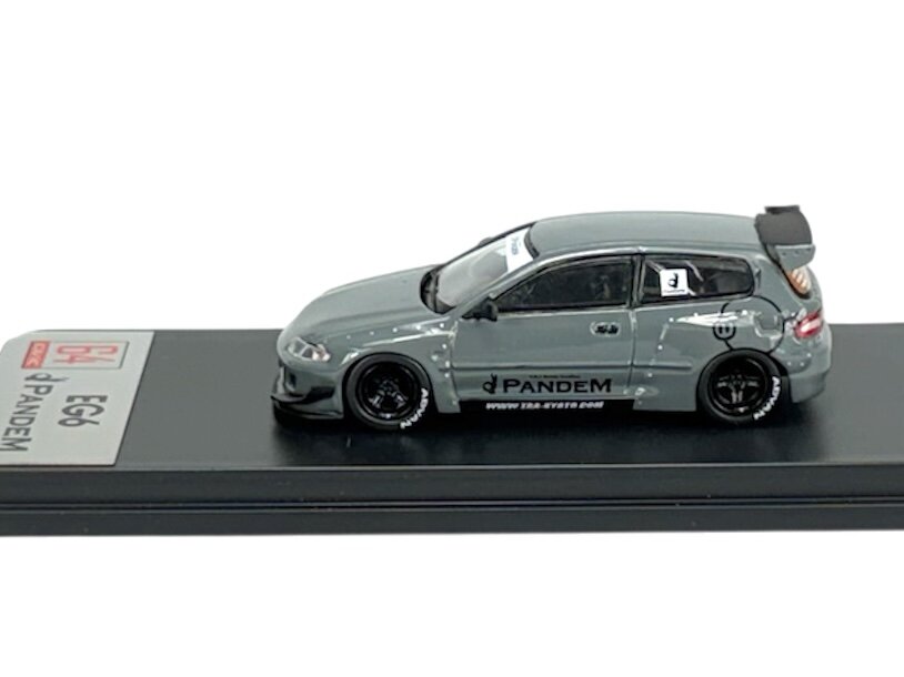 Model samochodu w skali 1:64 w kolorze szarym, z napisem \'PANDEM\' na boku. Samochód umieszczony jest na czarnej podstawce z oznaczeniem \'EG6\'.